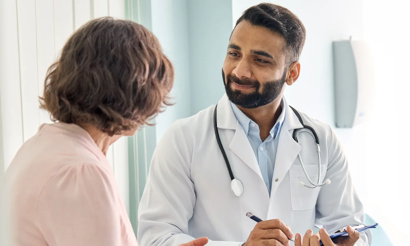 Physician seated taking notes with patient
