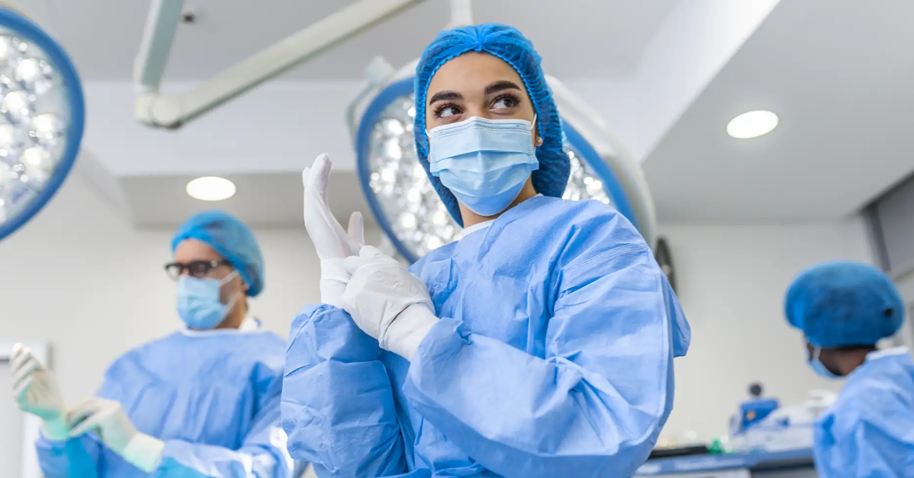 Surgeon in oerating room adjusting rubber gloves on hands