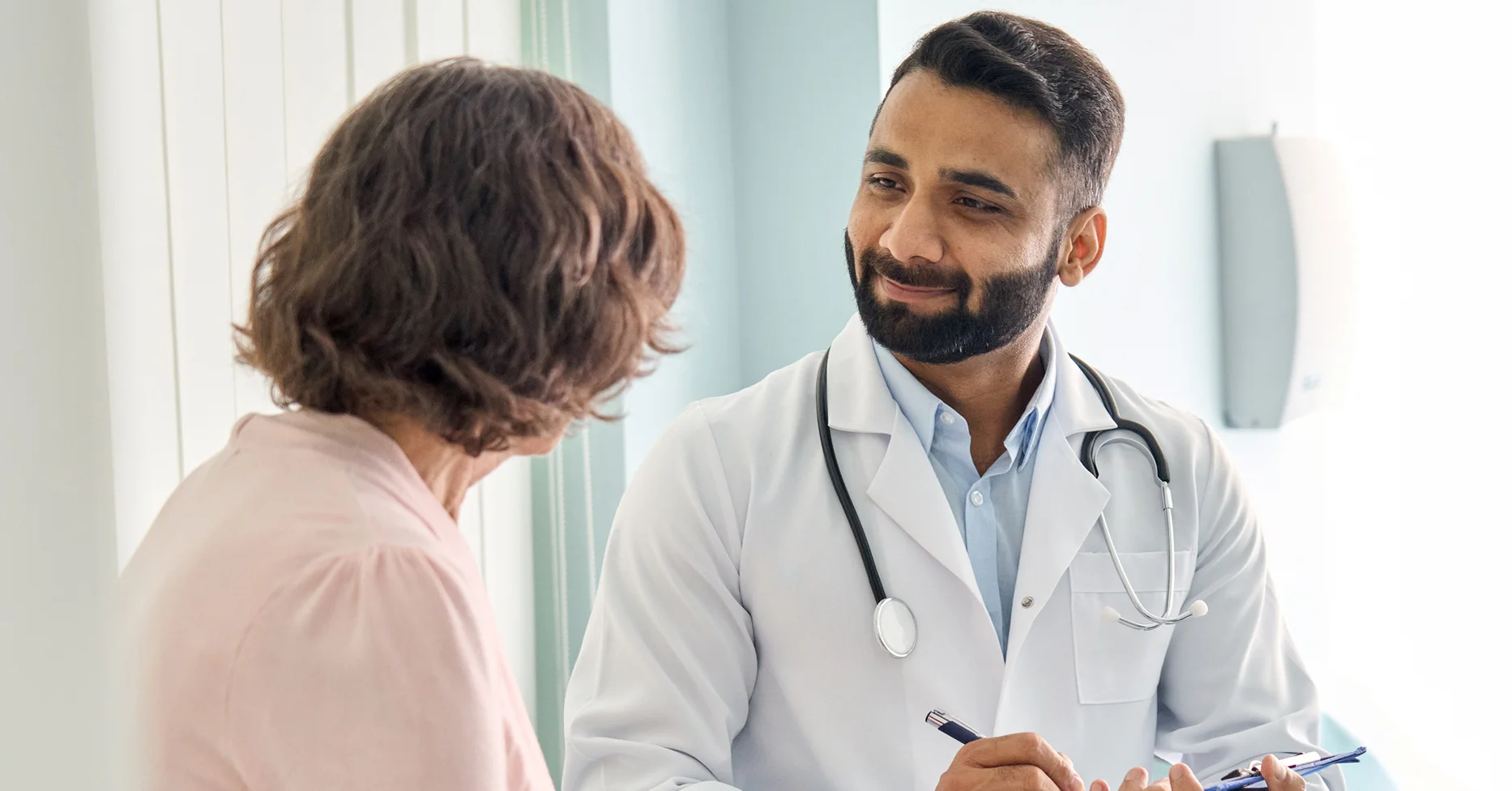 Physician seated taking notes with patient