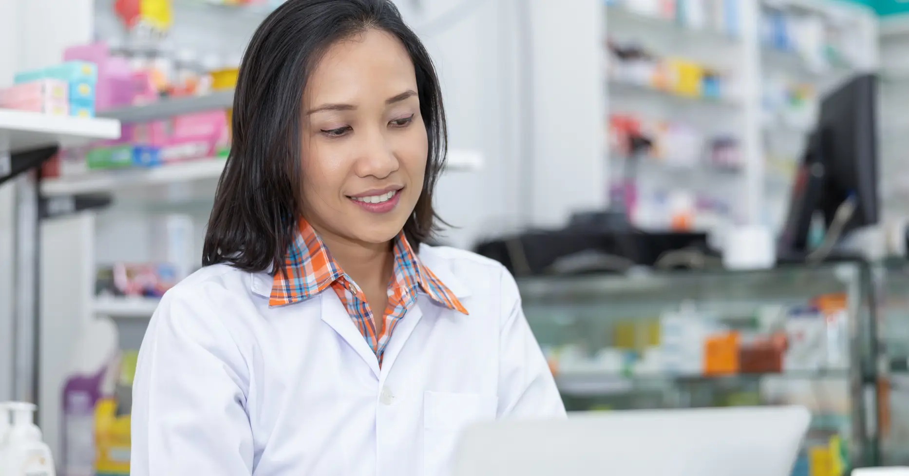 Pharmacist checking inventory on laptop in pharmacy