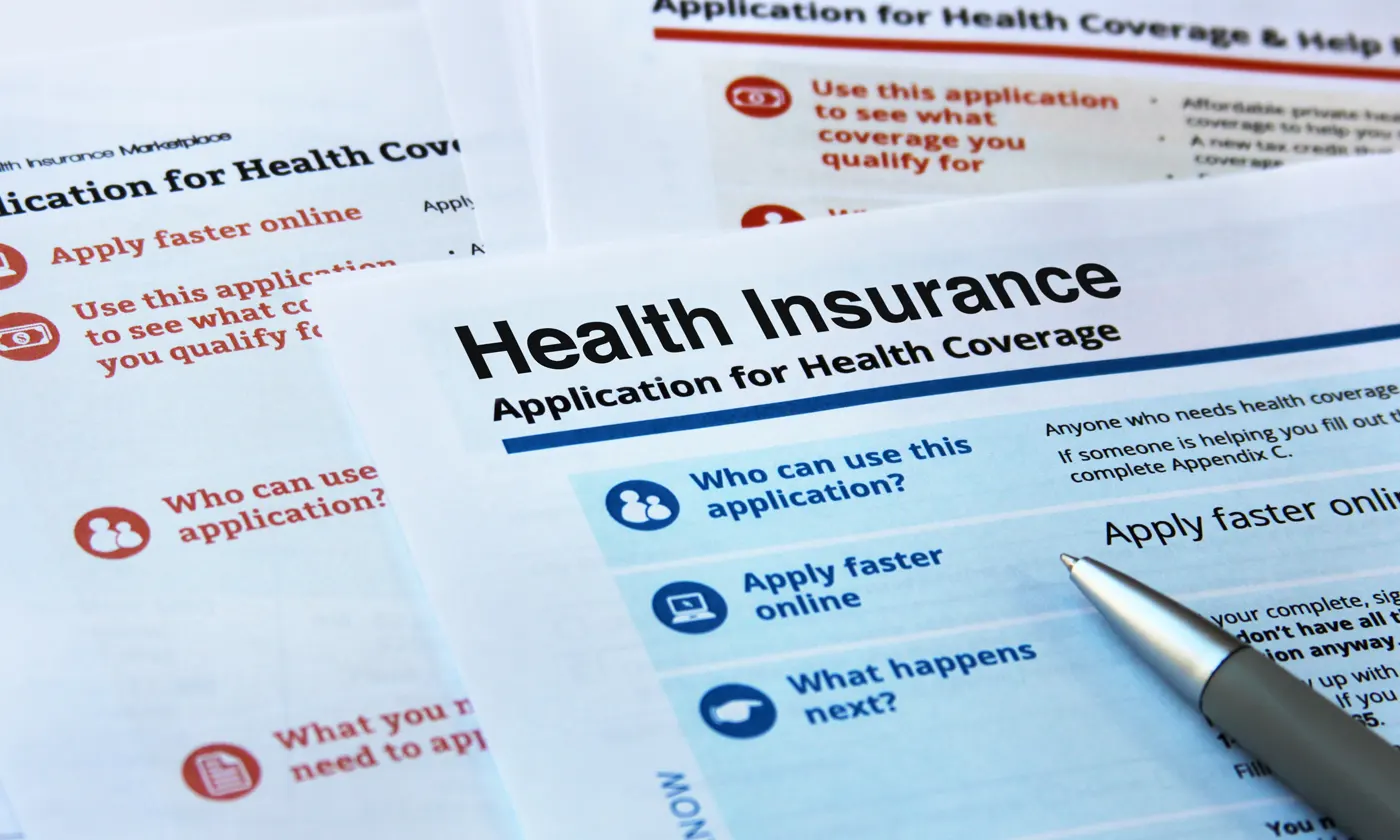 pen resting on top of various health insurance documents