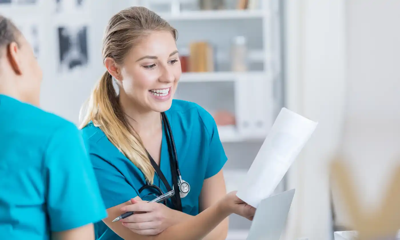 two smiling nurses talking and looking over paperwork