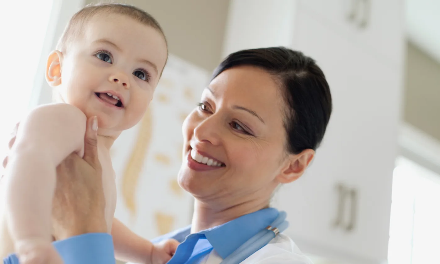 Close-up of smiling pediatrician holding happy baby